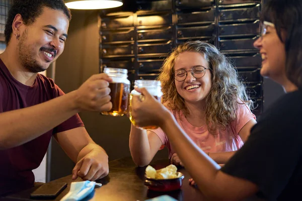 three friends smiling and toasting with beer in a bar celebrating the power of having left home after being locked up for a while