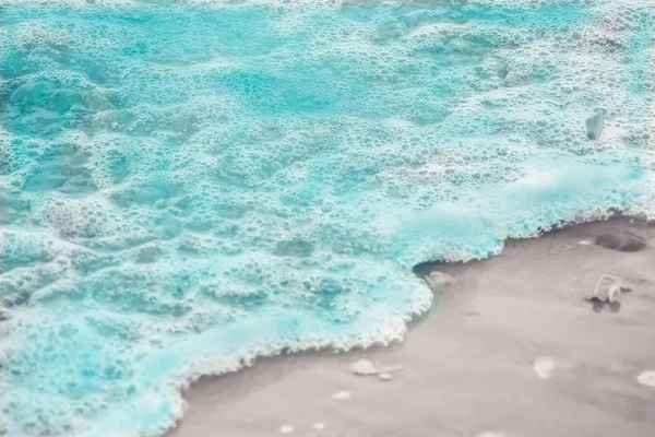 Cerca de las olas de agua de mar azul con burbujas blancas en la playa de arena — Foto de Stock