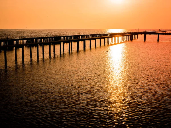 Low tide during sunset silhouette wooden pole and bridge through the sea beautiful orange sky background of nature — Stock Photo, Image