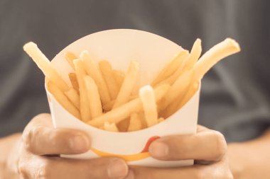 Ahşap masa arka plan üzerinde beyaz kutu içinde patates kızartma tutan adam