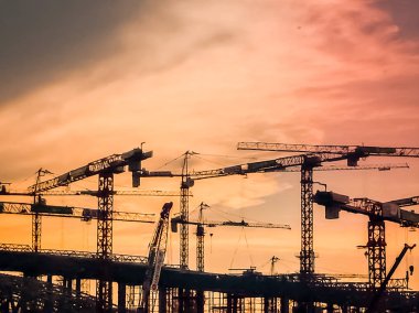 İnşaat silüeti yeni inşaat Simgesel Yapı binalar üzerinde günbatımında vinç. Kentsel arka plan