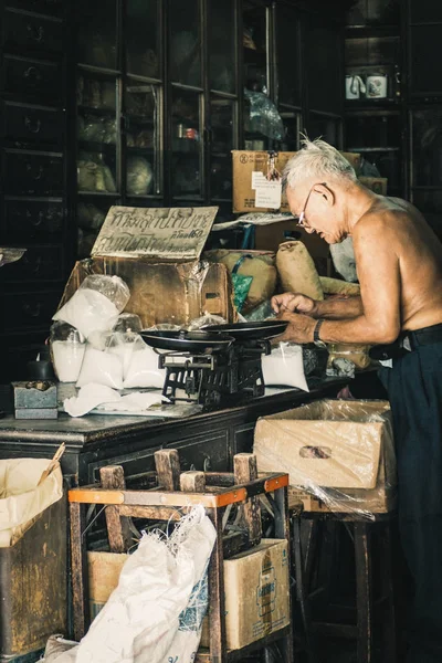 China town Bangkok Thailand December 2018 old chinese man in herbal shop or Chinese herb store dried wooden antique cupboard and storage for medical drug storage — Stock Photo, Image