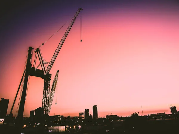 Jasny różowy zachód słońca. Domy i konstrukcje przemysłowe przed pięknym nieba zachód słońca. Pejzaż miejski, krajobraz przemysłowy. — Zdjęcie stockowe