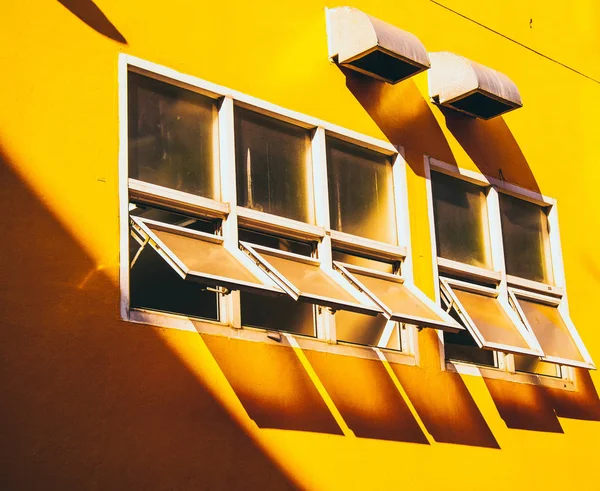 Żółta ściana ze szklaną ramą okienną. cień przez szkło lato koncepcja budynek tło — Zdjęcie stockowe