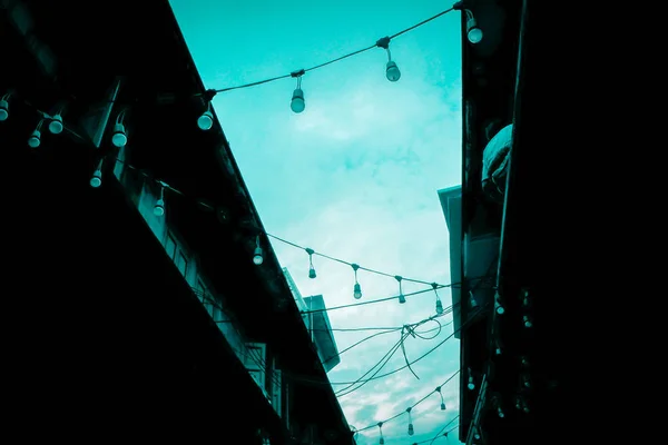 Dekorativa utomhus sträng lampor glödlampa hängande på El post i gatu nattmarknaden nattetid — Stockfoto