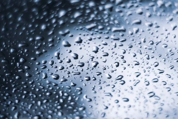 Chuva gotas de água em tom de azul sentindo azul através da natureza janela influenciado fundo — Fotografia de Stock