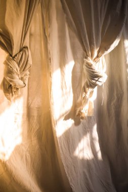 Penceredeki beyaz keten perdeler üzerinde güneş ışığı parlıyor ve güzel ışık ve gölge dokusu oluşturuyor. Doğa ve konfor tasarımı. Doğa kavramı ile yaşamak.