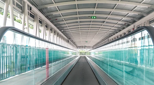 Ο σύγχρονος διάδρομος των κυλιόμενων κλιμάκων κινείται μπροστά και οι κυλιόμενες κινούνται προς τα πίσω στο διεθνές αεροδρόμιο. Κυλιόμενες σκάλες είναι δυνατότητα μεταφοράς υποστήριξης — Φωτογραφία Αρχείου