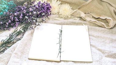 Boş beyaz kağıt defter ve çiçek dekorasyonu. Beyaz bir doğal tebrik kartı; keten arka plan