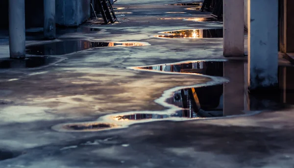 Puddle water reflection on ground. Parking lot with abstract water puddle reflection. Urban life concept idea.