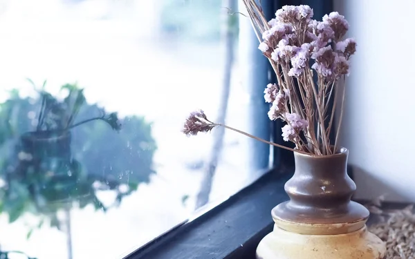 A small plant pot displayed in the window. Bouquet of flowers near window with curtain . lifestyle for living home idea