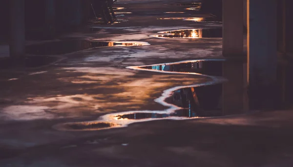 Puddle water reflection on ground. Parking lot with abstract water puddle reflection. Urban life concept idea.