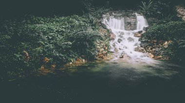 Sabah sisi şelalenin üzerinde yükselir canlı yeşil bir doğa manzarasıyla çevrilidir.