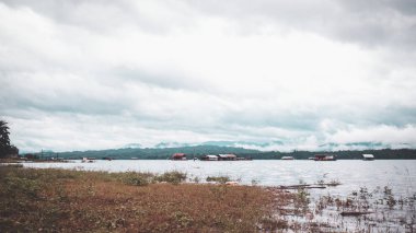 Göl kenarındaki rafting evi. Kanchanaburi Tayland 'ın arka planında sisli ve güzel bir manzara.