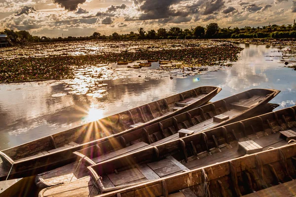 水面にはピンクの蓮池の木製のボートの横に日光 タイの古い木のボートと赤い蓮の花 ボートは日没時に池の表面に浮かぶThung Bua Daeng水上マーケット — ストック写真
