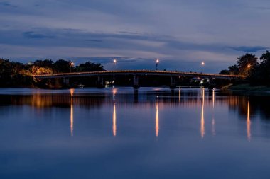 Ratchaburi Tayland 'da gece vakti nehir üzerindeki eski tren köprüsünün uzun pozlu fotoğrafı.