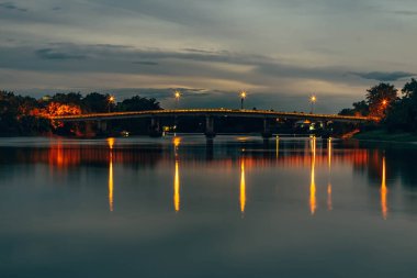Ratchaburi Tayland 'da gece vakti nehir üzerindeki eski tren köprüsünün uzun pozlu fotoğrafı.