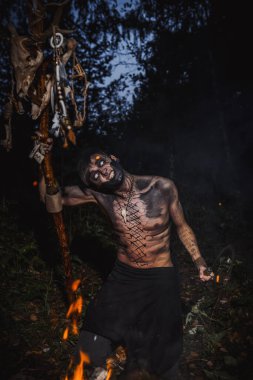 Ormanda vücudunda işaretler olan bir büyücü.