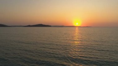 Yunan adasında deniz ufku üzerinde turuncu ve altın gün batımı