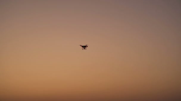 Silhouette of drone with digital camera flying on sunset. — Stock Video