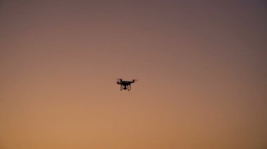 Gün batımına karşı uçan drone quadcopter silueti 