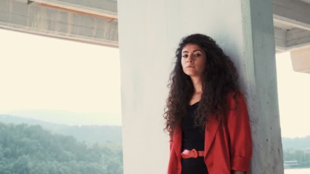 Chica reflexiva con vestido negro y chaqueta roja mirando el bosque — Vídeo de stock