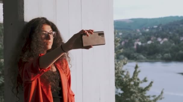 Morena encantadora tirando selfies no canteiro de obras com lago no fundo — Vídeo de Stock