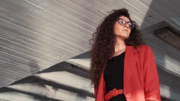 Elegancka damska modelka z okularami i czerwoną kurtkę z widokiem na lewą — Wideo stockowe