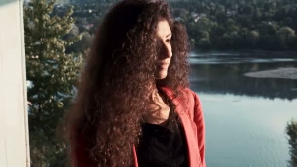 Красива жінка дивиться в озеро, сидячи на будівництві — стокове відео