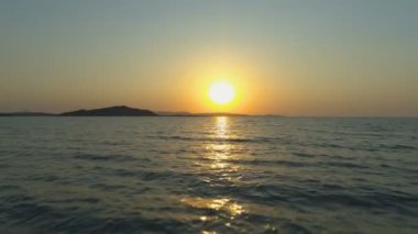 Parlak turuncu gündoğumuna karşı dalgalar ile deniz yüzeyinin havadan drone görünümü