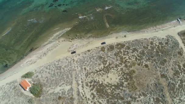 Drone siguiendo coches que conducen lento en la carretera costera rocosa de la playa en Lemnos, Grecia — Vídeo de stock