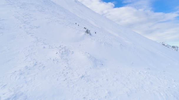 Imágenes aéreas de aviones no tripulados montaña cubierta de nieve en el invierno y el grupo de turistas que bajan — Vídeo de stock