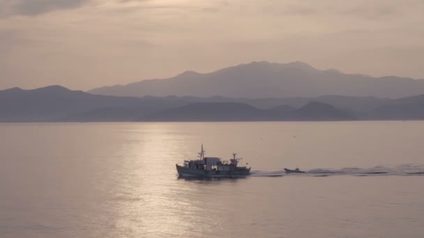 Scena magica di nave in mare calmo che attraversa il sentiero del sole al tramonto con cielo nuvoloso — Video Stock