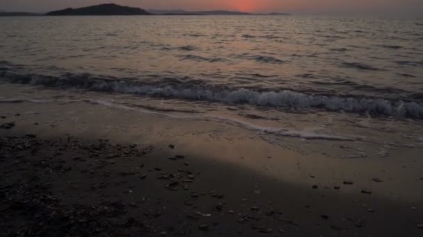 Relajante mar olas estrellándose en la playa con la puesta de sol roja en el fondo — Vídeos de Stock