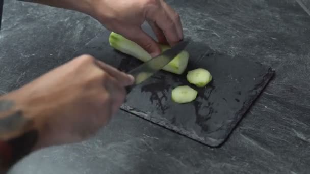 Gros plan sur les mains masculines coupant le concombre, faire de la salade. Chef coupant des légumes . — Video