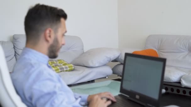 Männlicher digitaler Nomade, der von zu Hause aus am Laptop arbeitet und Notizen mit dem Stift macht — Stockvideo