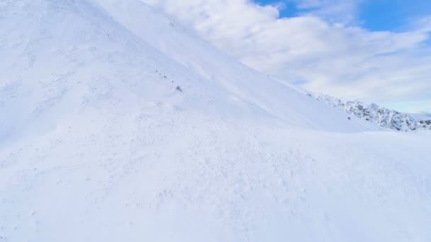 Muitas pessoas descendo a montanha no dia ensolarado de inverno com céu azul — Vídeo de Stock