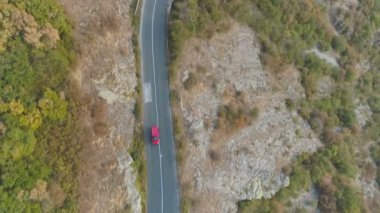Drone sonbahar gününde tek başına kayalık dağ yolu sürüş kırmızı araba izleyin