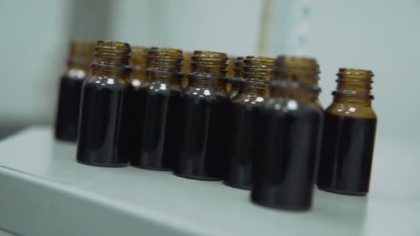 Botellas de cuentagotas llenas de aceite de bacalao farmacéutico negro — Vídeo de stock