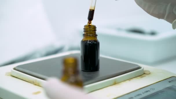 Olhar próximo da mão dos cientistas usando o conta-gotas e o frasco de enchimento com óleo de CBD no contrapeso eletrônico — Vídeo de Stock
