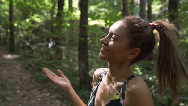 Фітнес жінка в спортивному одязі відчуває себе гарячим після ранкового бігу в лісі в спекотний літній день — стокове відео