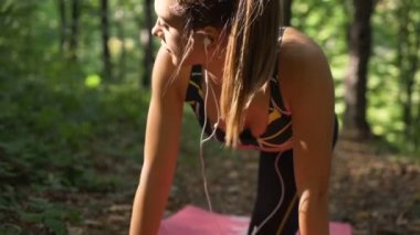 Sabahın erken saatlerinde parkta çalışırken kulaklıkla müzik dinleyen çekici bir kız.