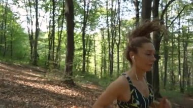 Müzik dinleyen ve ormanda koşan zinde bir kızın yakın görüntüsü