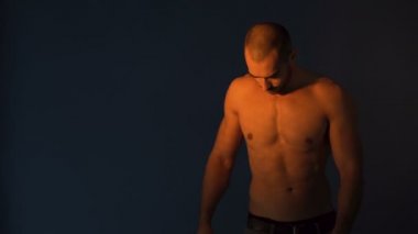 Fitness modeli karın kaslarını esnetiyor, koyu arkaplanda izole karın kaslarını gösteriyor.