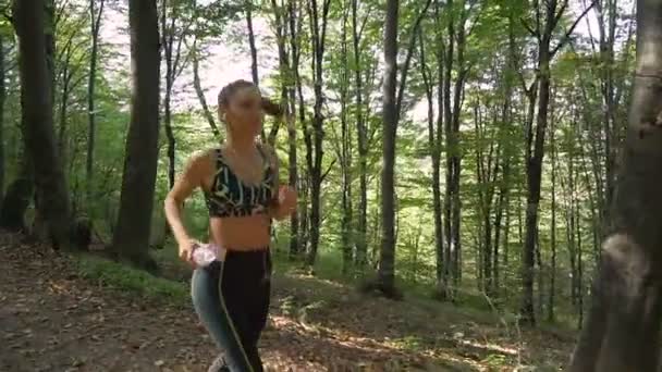 Slow motion footage of brunette fitness girl in sportswear with earphones jogging — Stock Video