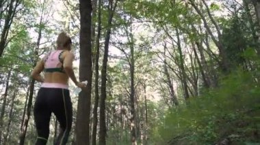 Ormanda koşan, ağaç gövdelerinden atlayan bir kızın kamera görüntüsü.