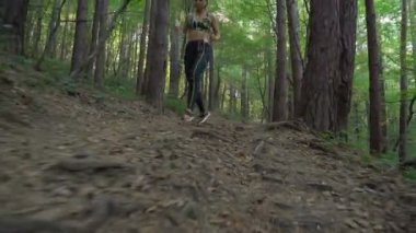 Atletik esmer, koşu ayakkabılarıyla ormanda koşuyor, orman yolunda koşuyor.