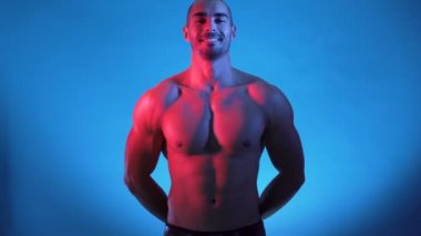 Yakışıklı jimnastikçi stüdyoda üstsüz duruyor.