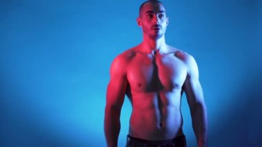 Yakışıklı fitness eğitmeni kaslı gövdeyi esnetiyor ve 6 paket gösteriyor.