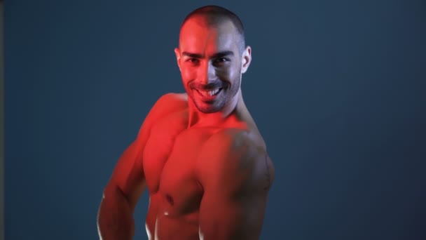 Bodybuilder glimlachen en flexen grote spieren, knipoog naar de camera — Stockvideo